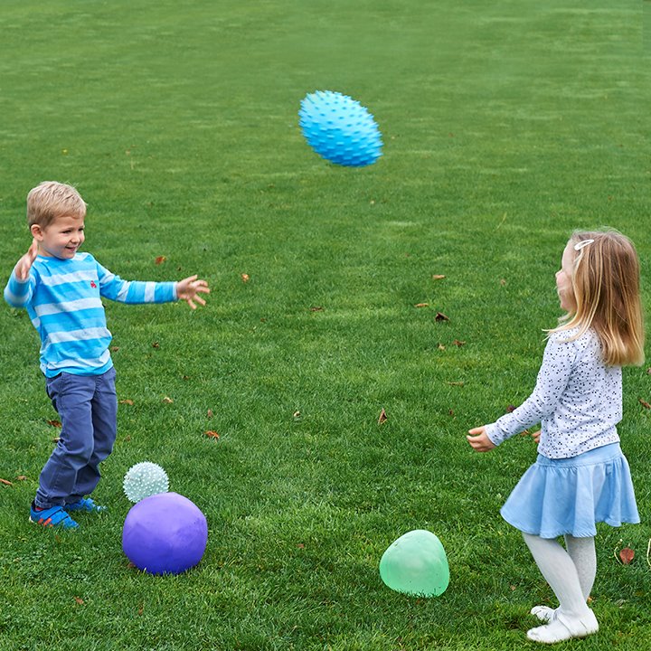 Children playing catch with odd balls outside