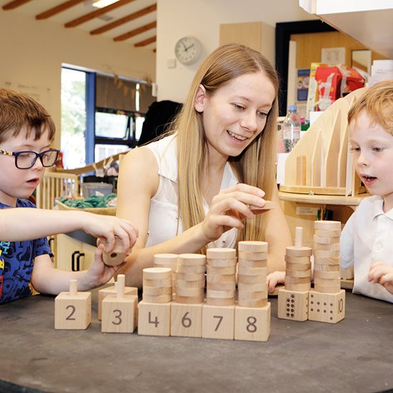 Teacher helping two children with number stacker