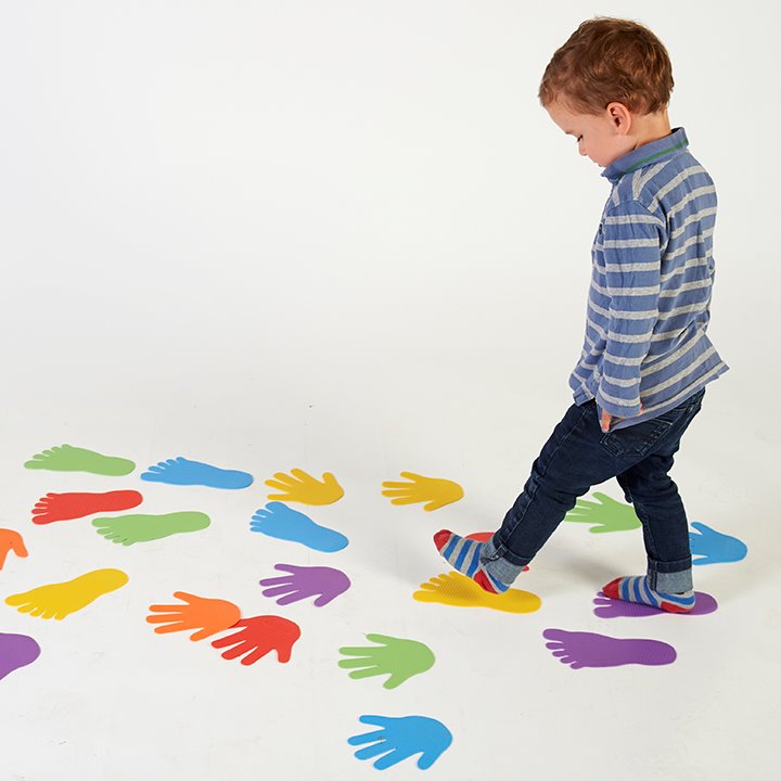 Boy stepping across colourful path of hands and feet floor markers