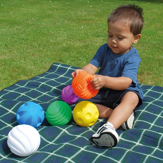 Child on blanket playing with tactile balls