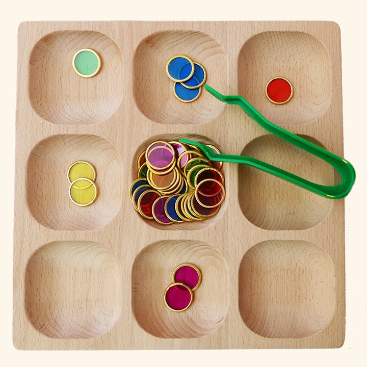 Metal counting chips sorted into wooden tray with green plastic tweezers