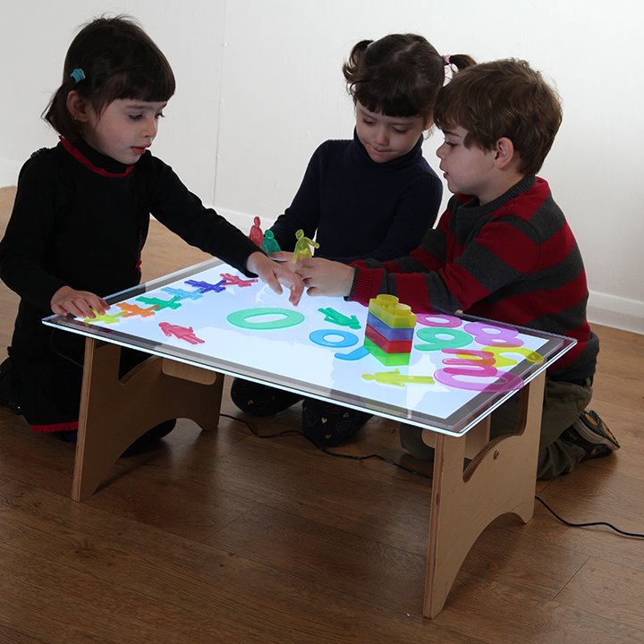 Children gathered around and playing with the light up table-top