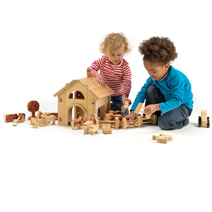 Two little children playing with farmyard set