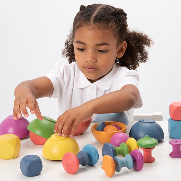 Child playing with Tactile smooth solid beechwood loose parts in the seven colours of the rainbow