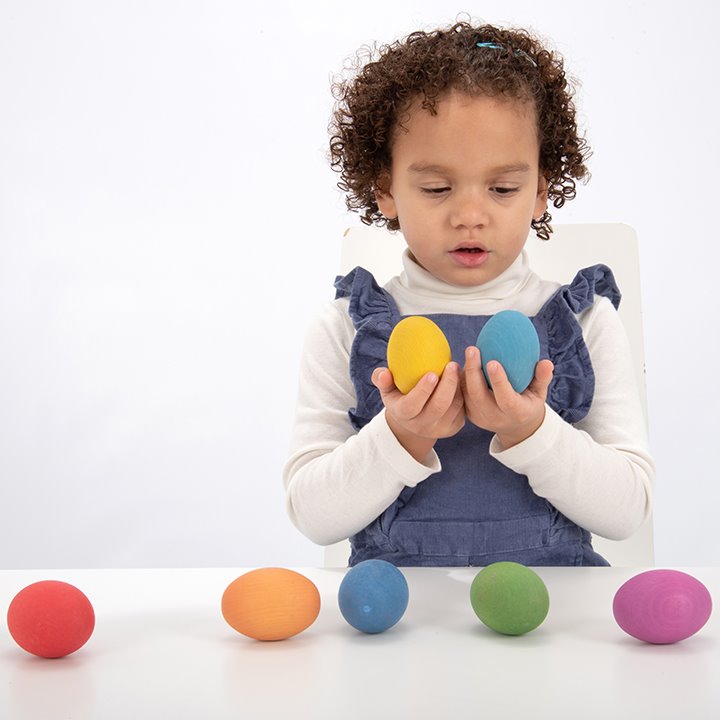 Child with Beautifully smooth coloured wooden eggs - ideal for loose parts and heuristic play