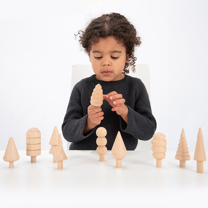 Child picking up wooden tree