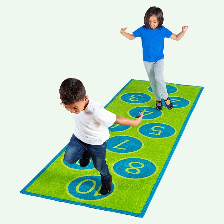 Two children jumping on hopscotch carpet