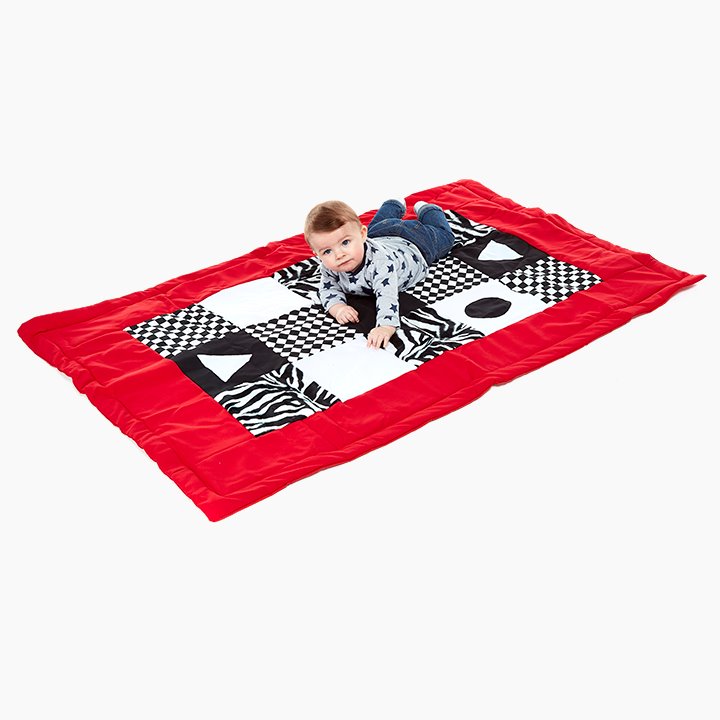 Black and white patterned tummy time mat with a red trim