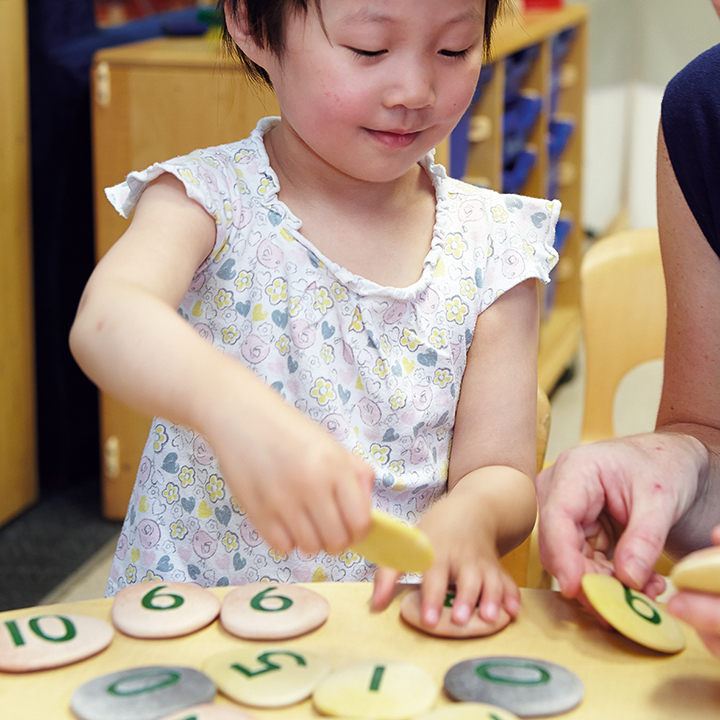 Little girl playing with numbered pebbles