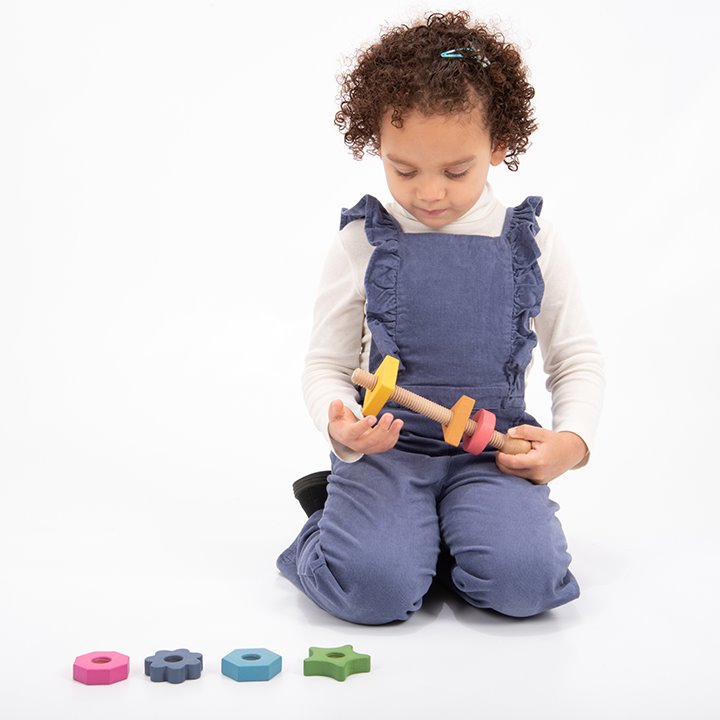 Child playing with A giant bolt with seven nuts in seven shapes and seven colours!