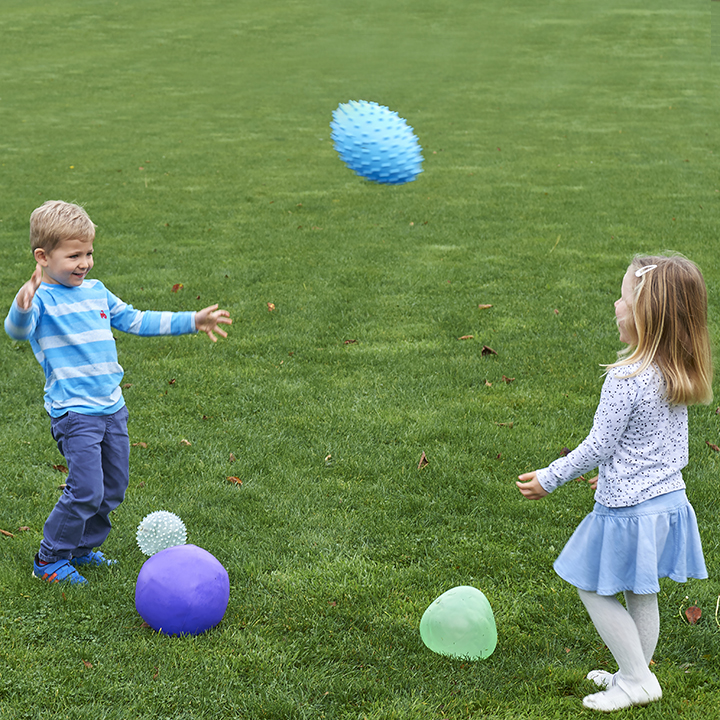Children playing catch with odd balls outside