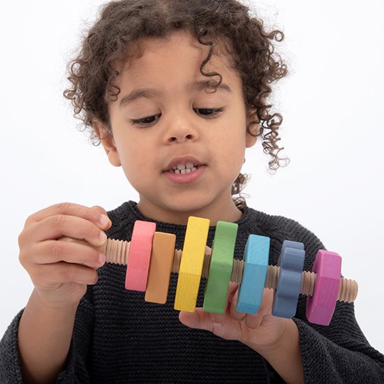 Child twisting A giant bolt with seven nuts in seven shapes and seven colours!