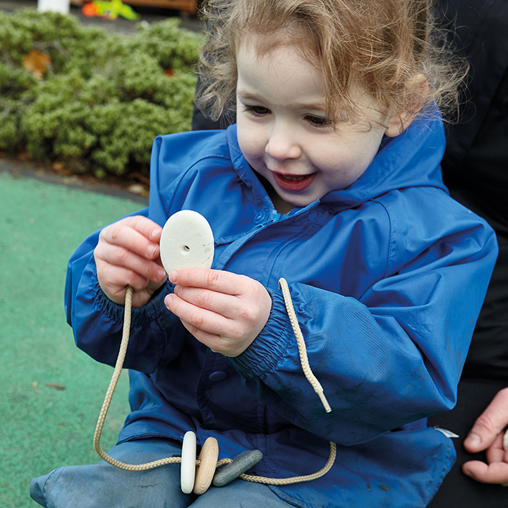 Child threading pebbles