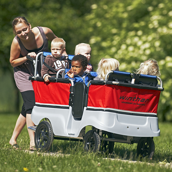 Adult pushing children in kiddy bus