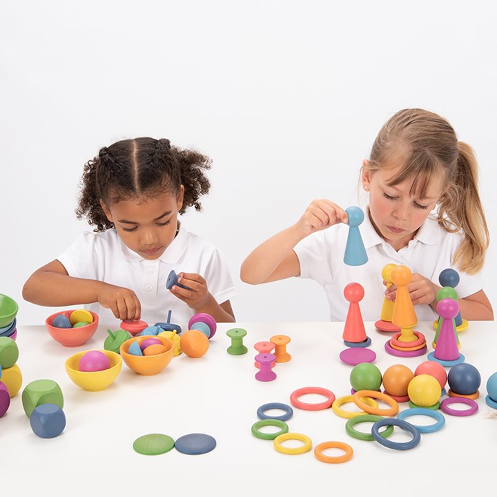 Two children cooperative play with Tactile smooth solid beechwood loose parts in the seven colours of the rainbow
