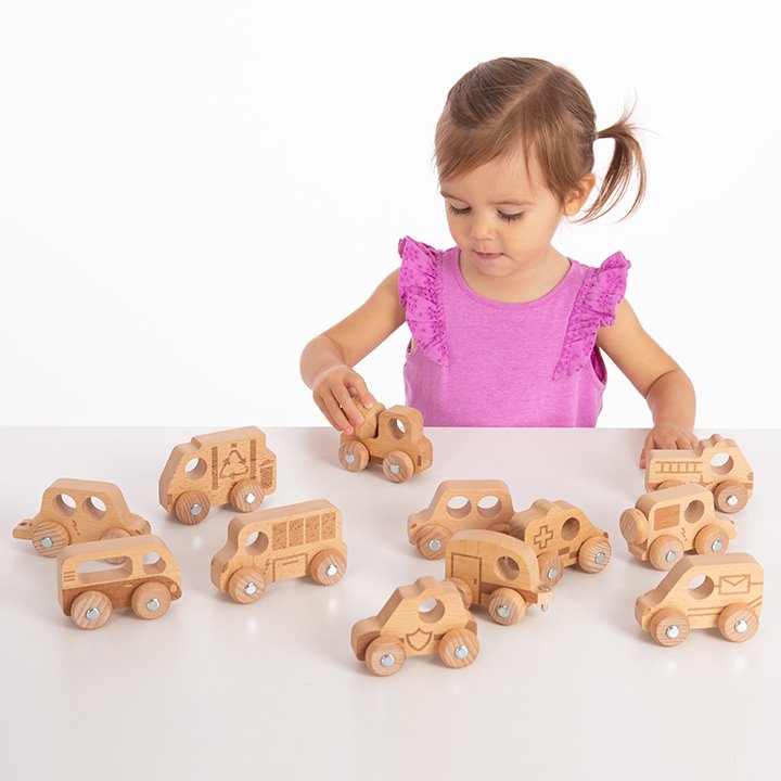 Little girl playing with wooden vehicles