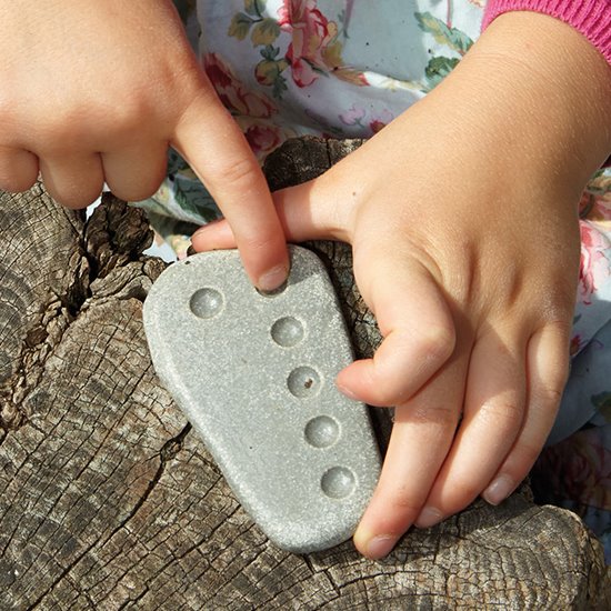 Child fingers counting stones