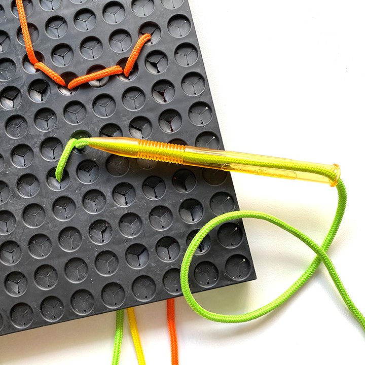 Demonstration of pushing lace through play board holes