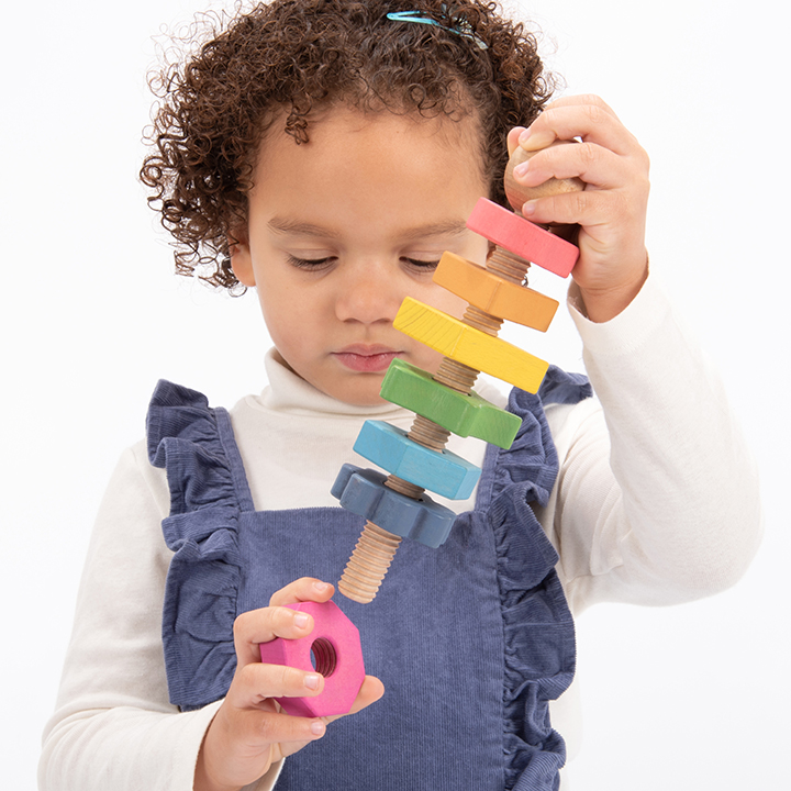 Child attaching nut to A giant bolt with seven nuts in seven shapes and seven colours!