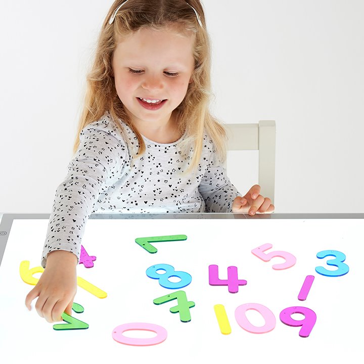 Little girl organising numbers on a light surface