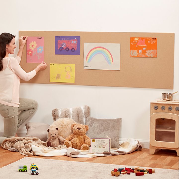Woman creating a display on notice board mounted on wall